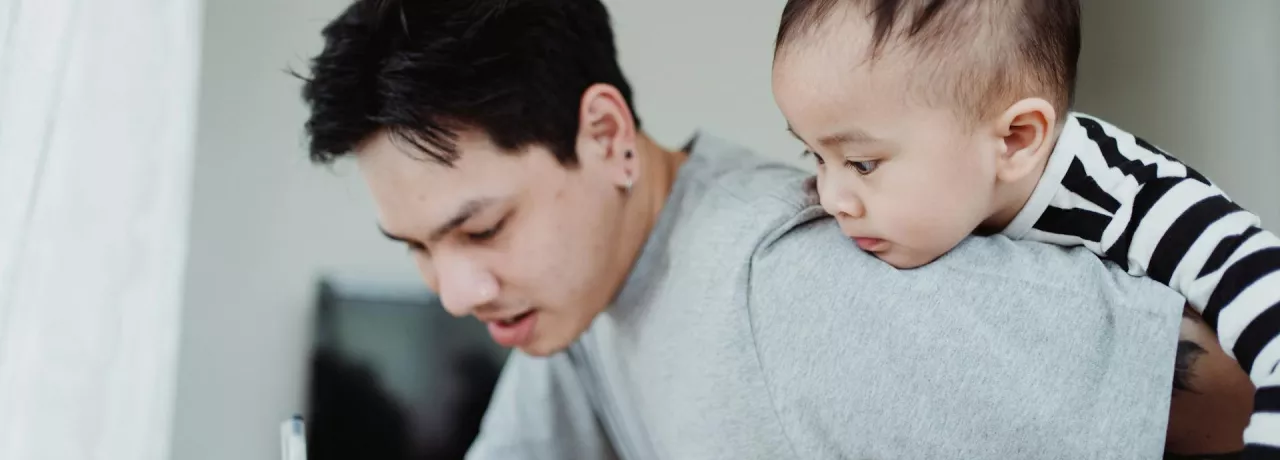 un père qui travaille en gardant son bébé
