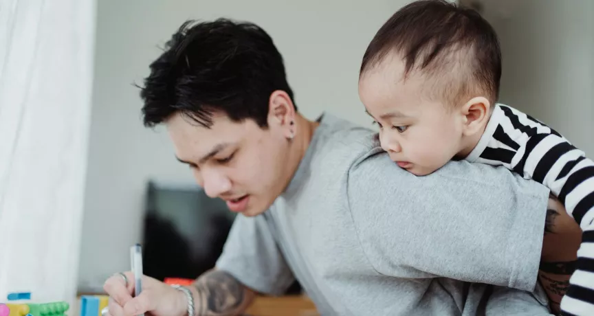 un père qui travaille en gardant son bébé