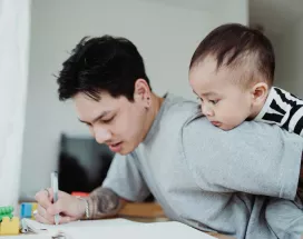 un père qui travaille en gardant son bébé
