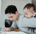 un père qui travaille en gardant son bébé