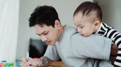 un père qui travaille en gardant son bébé