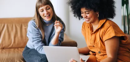 Two women looking at a laptop smiling